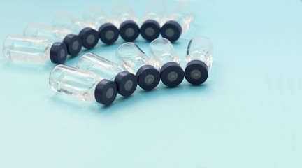 Medicine in vials, ready for vaccine injection on blue background. Cancer, painand diabetes treatment, pharmaceutical medicine concept .
