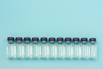Medicine in vials, ready for vaccine injection on blue background. Horizontal composition. Front view.