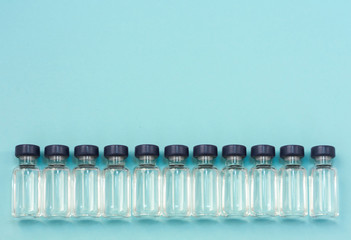 Medicine in vials, ready for vaccine injection on blue background. Horizontal composition. Front view.