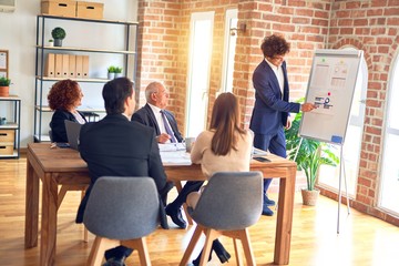 Group of business workers smiling happy and confident in a meeting. Working together looking at presentation using board and charts at the office.