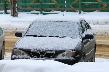 Car on a city street in winter covered with snow