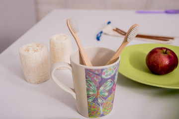 Bamboo toothbrushes, washcloths, cups and plates on the white table 