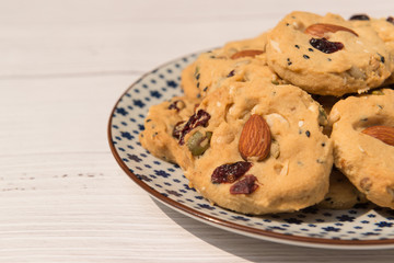 Multigrain cookies (almond, cranberries, cashew nut, pumpkin and sasame seeds) on five-pointed flower pattern, wooden background top view.