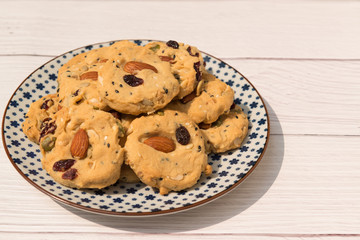 Multigrain cookies (almond, cranberries, cashew nut, pumpkin and sasame seeds) on five-pointed flower pattern, wooden background top view.