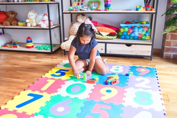 Fototapeta premium Beautiful toddler girl playing with construction blocks at kindergarten