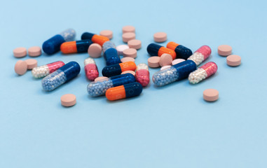 Heap of colorful pills, tablets, capsules on blue background. Drug prescription for treatment medication health care concept wth copy space.