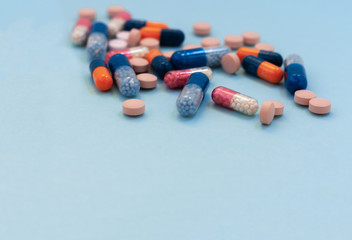 Heap of colorful pills, tablets, capsules on blue background. Drug prescription for treatment medication health care concept wth copy space.