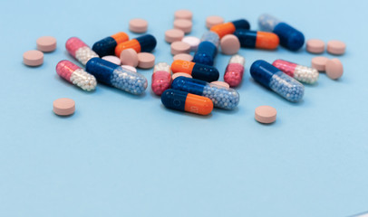 Heap of colorful pills, tablets, capsules on blue background. Drug prescription for treatment medication health care concept wth copy space.