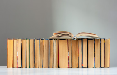 Open hardback book, diary, fanned pages on stack of books on white table in library. Books stacking. Back to school concept. Copy Space. Education learning background.