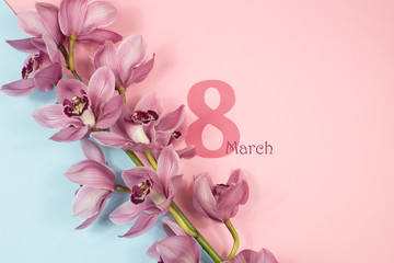 Fototapeta na wymiar March 8. Women's day. Branch of a pink Cymbidium Orchid on a pink-blue background with hearts