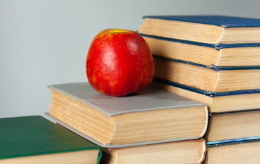 stack of hardback books on white table with red apple. Books stacking. Back to school concept. Copy Space. Education learning background.