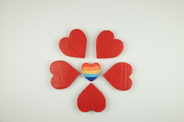 concept of traditional relationships and LGBT, a heart painted in rainbow colors surrounded by red hearts