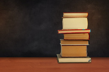 Back to school, pile of books with empty black school board background, education concept.