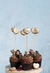 cupcakes with chocolate cream with hearts on a light blue background. place for text or congratulation