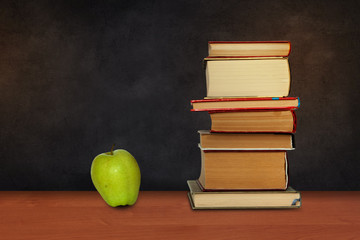 Back to school, pile of books and green apple with empty green school board background, education concept
