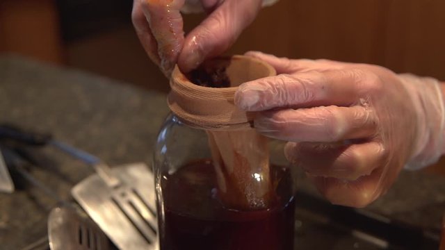 Squeezing essential cannabis oil mix filled in pantyhose, close up