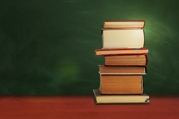 Back to school, pile of books with empty green school board background, education concept.