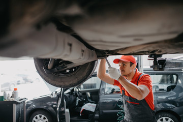 Portrait of a mechanic repairing a lifted car in auto center