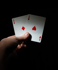 hand hold two red aces poker, the best pocket pair on a black background copy space. close up