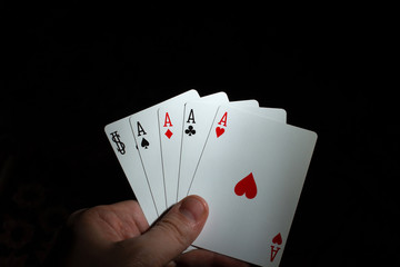 hand hold four aces and joker poker on black background copy space. close up
