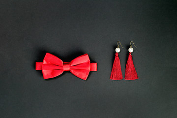 red bow tie and fancy earings. Flat lay on black background. 14 February. Passion, love and feelings St Valentine's Day Card celebration concept with copy space