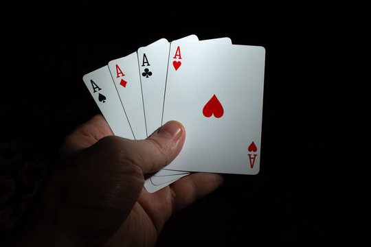 hand hold four aces poker on black background copy space. close up