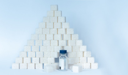 Sugar addiction, insulin resistance, unhealthy diet, sugar cubes pyramid and bottles of insulin on white background, diabetes protection medical concept, top view.