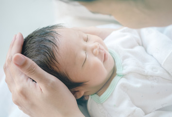 Obraz na płótnie Canvas Closeup a baby sleeping comfortably in the mother's arms