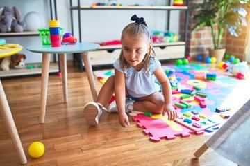 Young beautiful blonde girl kid enjoying play school with toys at kindergarten, smiling happy playing at home