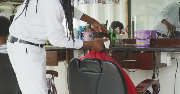 African man cutting African boy hair 