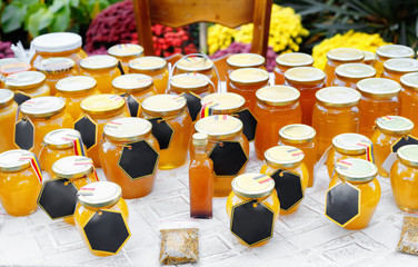  Assortment of honey jars at market stall. Sale of natural honey in fair outdoor.