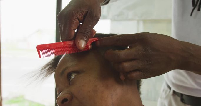 African man dividing the hair of the African woman