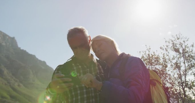 Senior couple searching direction on smartphone on mountains