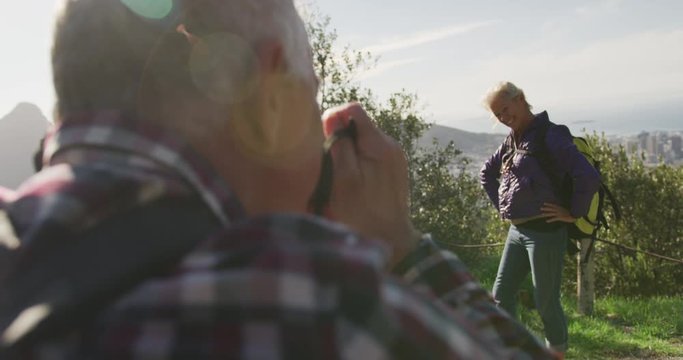 Senior man taking picture of senior woman on mountains