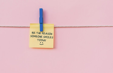 Motivational and inspirational quotes - Be the reason someone smiles today. Text on hanging paper...