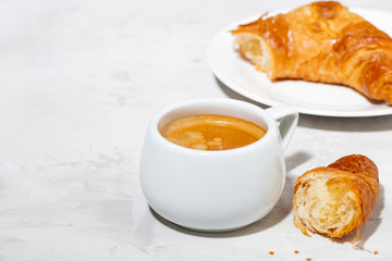 cup of espresso and fresh croissants on white background, closeup