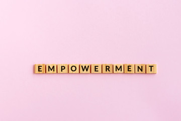 Empowerment text wood blocks. Pink background.