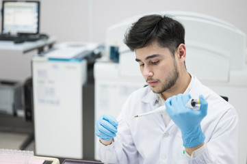 Scientist hand holding and using pipette drop reagent for blood chemical analysis.Laboratory equipment and medical treatment concept.Young man researcher in the his lab room.