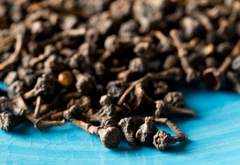 Heap of raw, dried cinnamon blossom buds spice on blue plate background