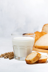 glass of milk, assortment of fresh bread on white table