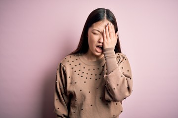 Young beautiful asian woman wearing fashion and elegant sweater over pink solated background Yawning tired covering half face, eye and mouth with hand. Face hurts in pain.