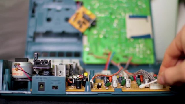 Cleaning the dust form the main circuit board inside of an old multi track analog tape recorder for a miniature audio engineering studio set up.