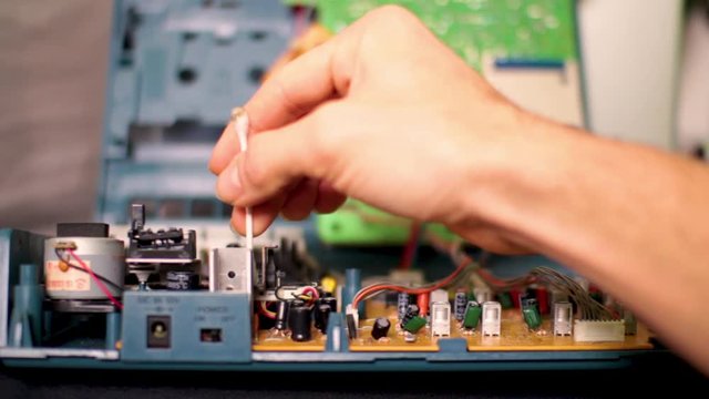 Cleaning the dust form the main circuit board inside of an old multi track analog tape recorder for a miniature audio engineering studio set up.
