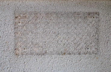 traces of an old rectangular plate on a white plaster wall