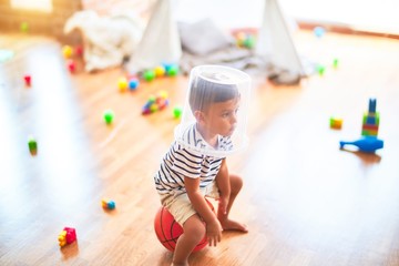 Fototapeta premium Beautiful toddler boy playing with plastic basket at kindergarten
