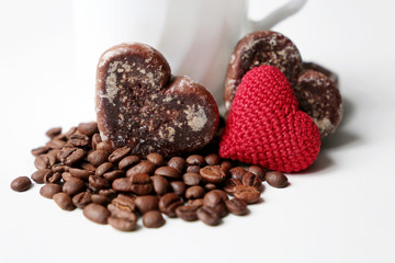 Valentine day romantic breakfast, cup of coffee, red knitted heart and gingerbreads with coffee beans on white background. Concept of love and care, morning dessert