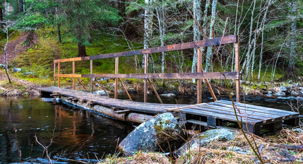 Fototapeta na wymiar Wooden bridge over a river in a forest in Sweden