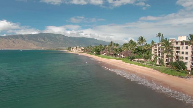 Aerial view of beautiful Kihei beach on Maui Hawaii with palm trees, mountains and buildings