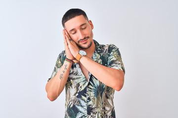 Young handsome man wearing Hawaiian summer shirt over isolated background sleeping tired dreaming and posing with hands together while smiling with closed eyes.