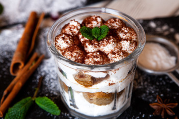 Tiramisu cake in glass, classic Italian dessert with mascarpone cream and cocoa. selective focus.